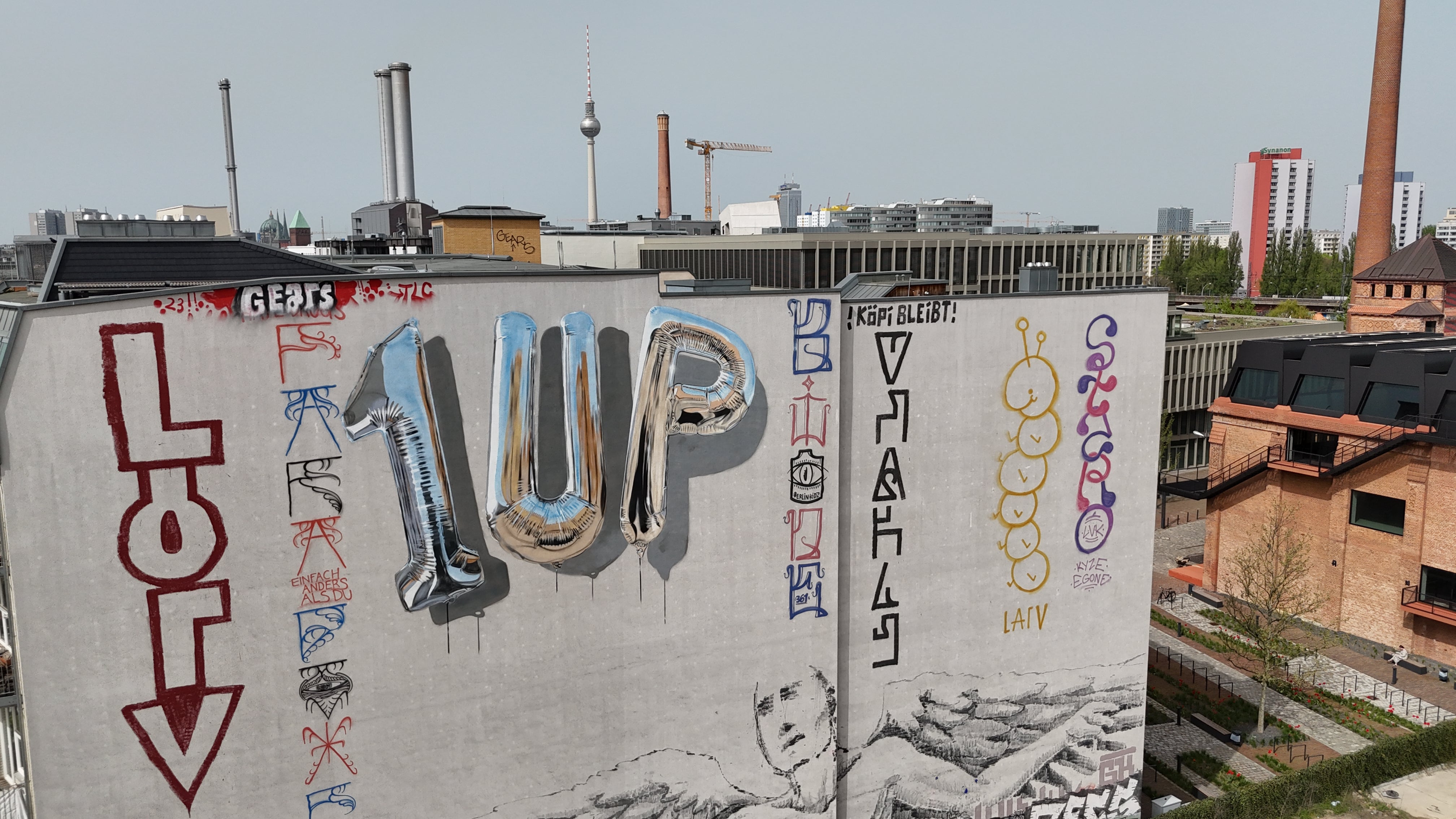 Fanakapan mural of reflective chrome balloon letters on a brick wall in Shoreditch, London, showing realistic highlights and shadows that create a 3D effect.
