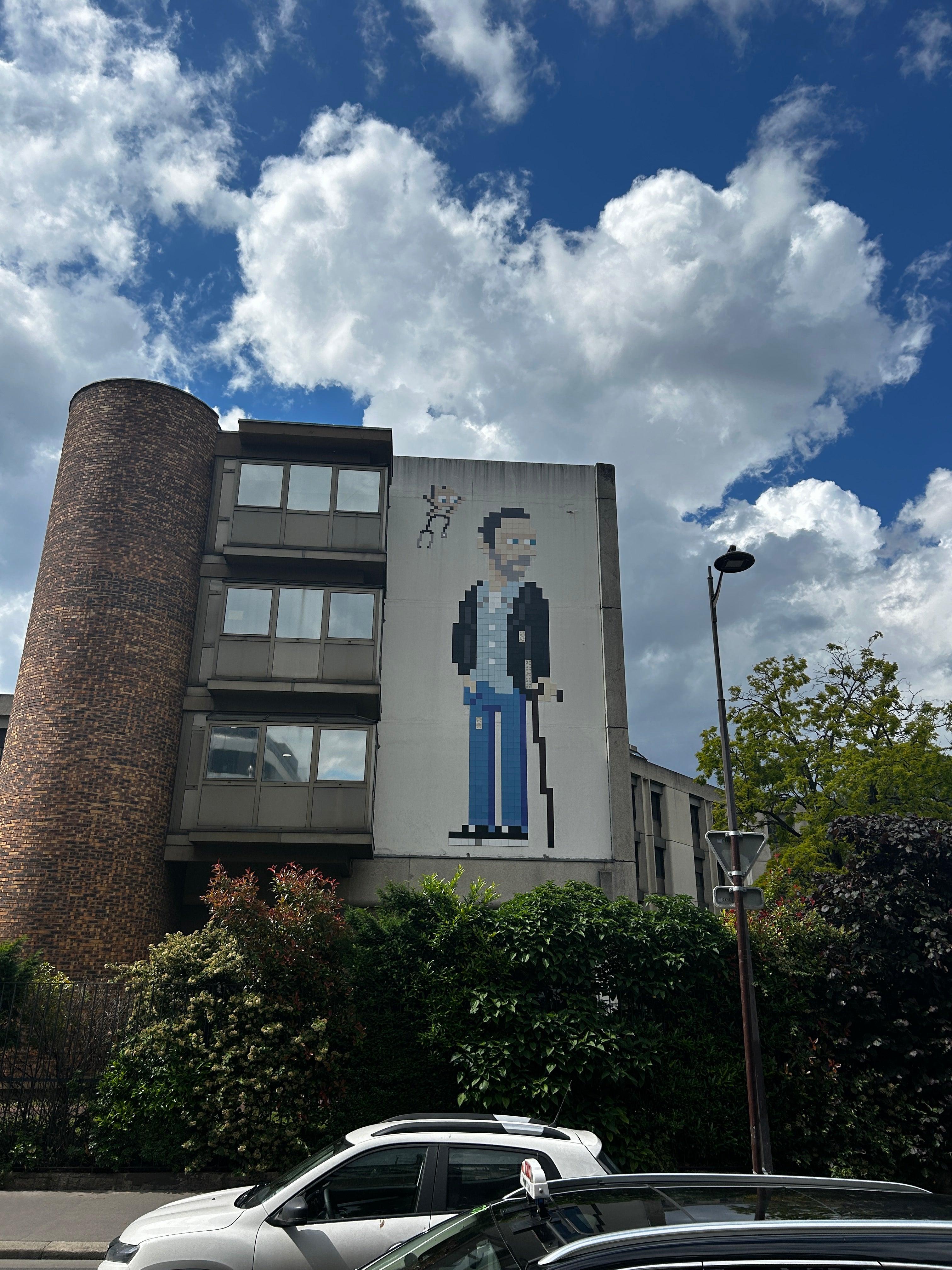 Mosaic artwork by French street artist Invader depicting the character Dr. House from the TV series “House M.D.”, created from small ceramic tiles in pixelated 8-bit style and installed on a Paris building facade.