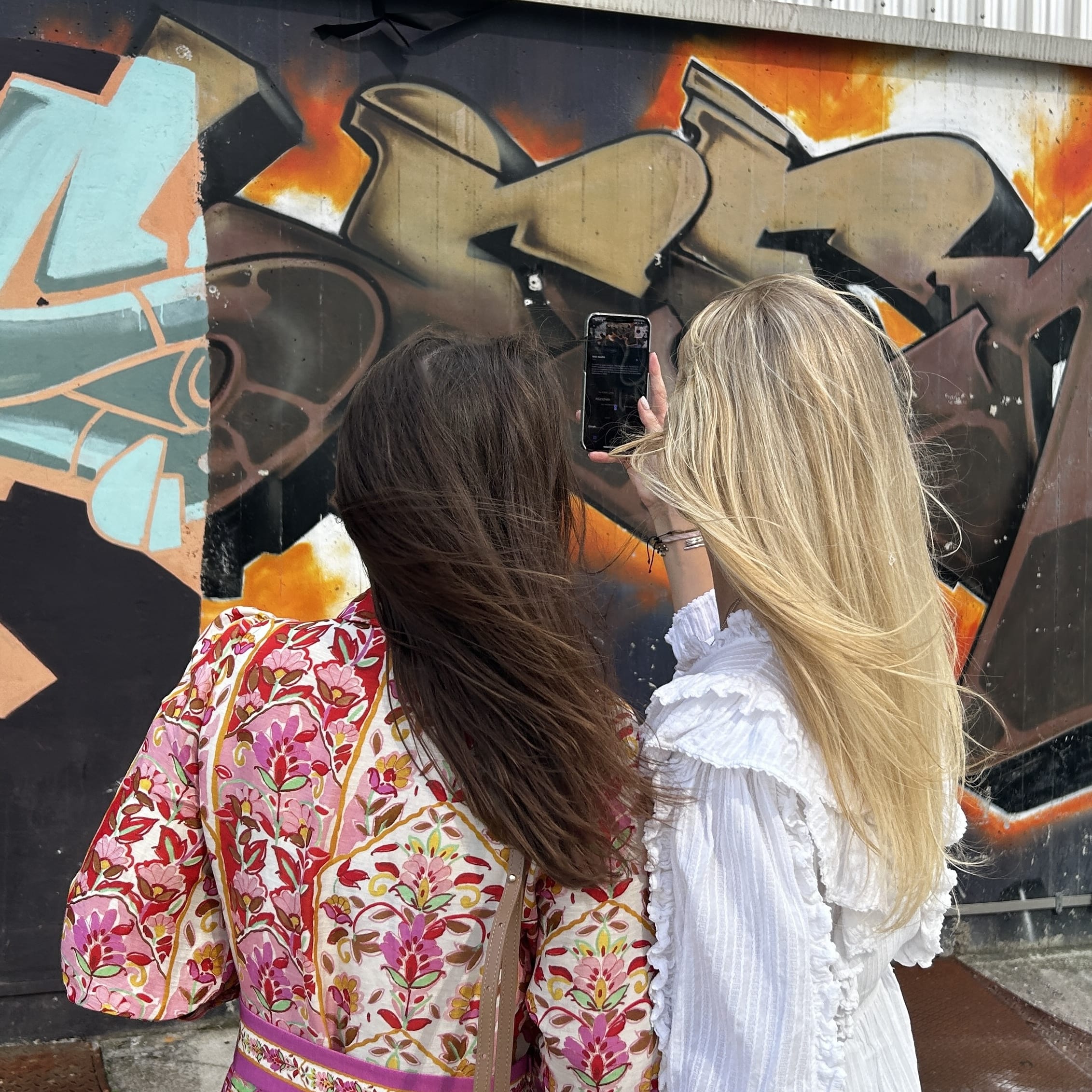 Two women exploring the Sternschanze district in Hamburg while playing the Street Art Game during a Street Art Tour Hamburg.