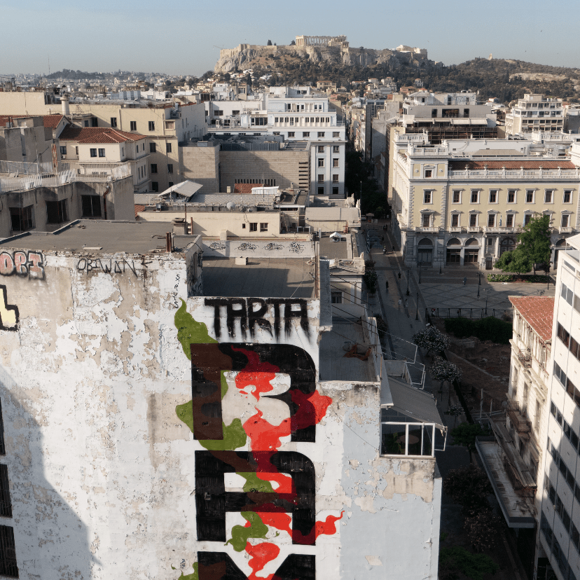 Street Art Tour Athens featuring the graffiti by Rams in the Psiri district with a view of the Acropolis in Athens.